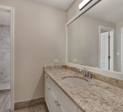 Guest bathroom with twin vanities and walk-shower accessible from living room