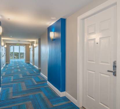 Clean, well-lit hallway offering easy access to the unit & a calm arrival experience