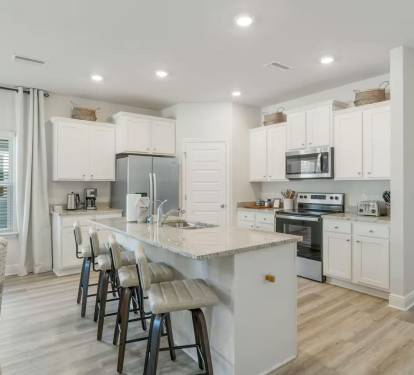 Modern kitchen with a 4-stool counter, microwave, stove, and spacious 2-door fridge