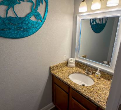 Located off the main hallway, the guest powder room is thoughtfully designed with warm lighting and upscale finishes.