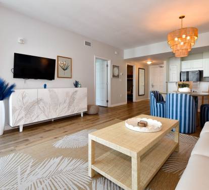Stylish living area w/ modern decor, warm lighting, and an open flow into the kitchen.