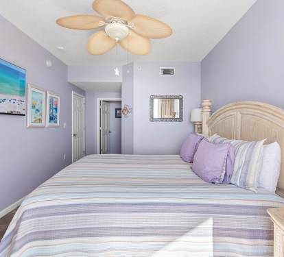 Primary bedroom w/ cozy bed setup & a relaxed, beachy atmosphere.