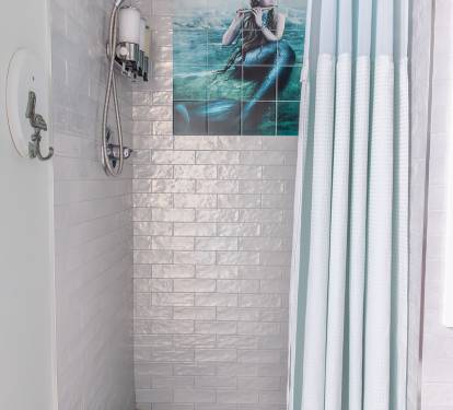 Step into the walk-in tile shower, where a mermaid adds a bit of coastal character to your routine. With a gentle shower head and bulk shampoo, conditioner, and body wash provided, it’s an easy place to wash away the day and unwind.