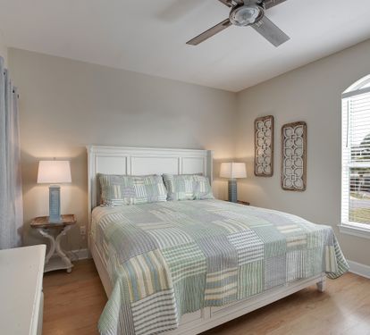 King bedroom with coastal bedding and natural light