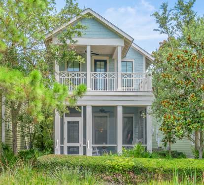 Charming exterior w/ coastal-style siding, balconies & lush landscaping that sets a welcoming first impression.