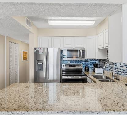 This modern coastal kitchen features granite countertops and sleek stainless-steel appliances. 
