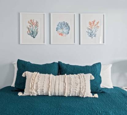 Sink into deep teal bedding under soft coastal art.