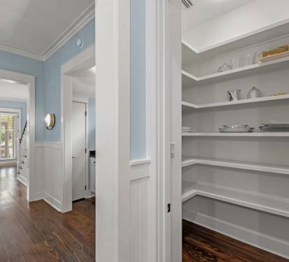 Walk-in pantry w/ open shelving, offering plenty of space for snacks and kitchen essentials.