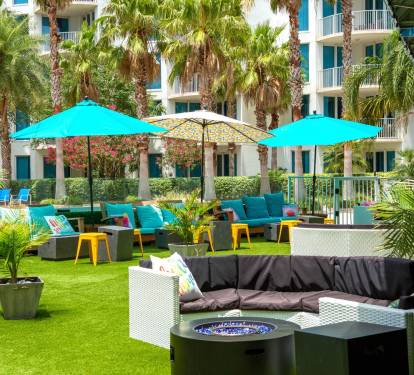 Inviting outdoor lounge w/ colorful seating, umbrellas, and a relaxed courtyard vibe.