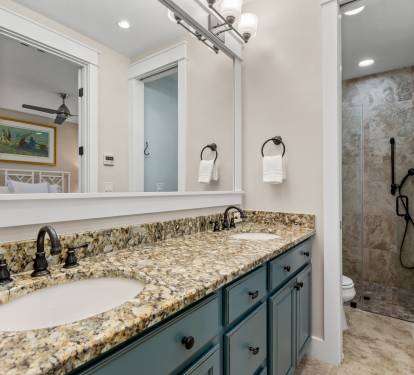 Walk-in shower w/ stone tile, glass enclosure & sleek fixtures for a spa-like feel.