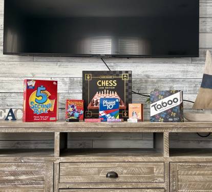 Entertainment console with TV and a selection of board games for guest enjoyment.