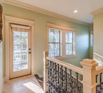 Second floor landing with glass door to upper deck porch, custom iron staircase and flooded with natural sunlight