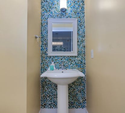 Even the guest half bathroom has an ocean vibe with the glass pebble wall