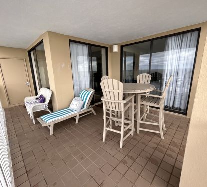 Beach view balcony seating with table and chairs, lounge chair and wicker sofa