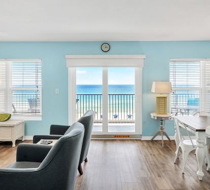 Panoramic view of living, dining, and kitchen area showing balcony beach view.