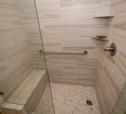 large walk-in shower in master bath with a tile bench