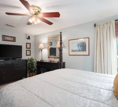 Master bedroom offers a queen bed, TV and beach view.