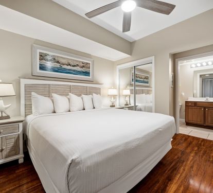 Bright coastal king bedroom with ensuite bath and ceiling fan