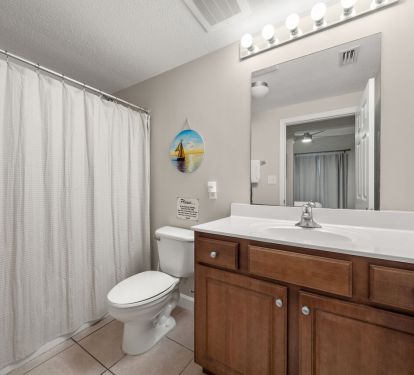 Clean coastal bathroom with tub shower, vanity lighting, and ample counter space