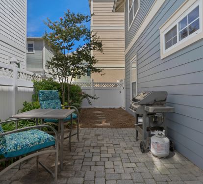 Private backyard and patio area with seating and gas grill.