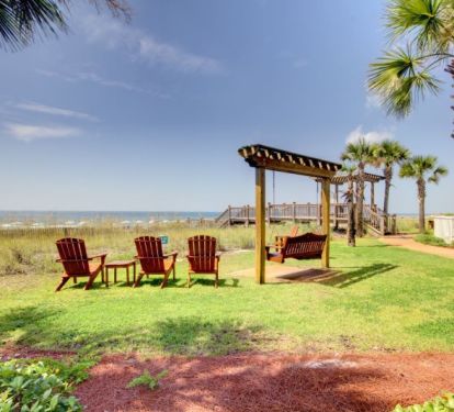 Adirondack chairs and swing overlooking the white sand and emerald green Gulf