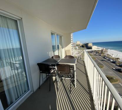 Gulf view balcony with table seating for 4 guests and a chaise lounge.