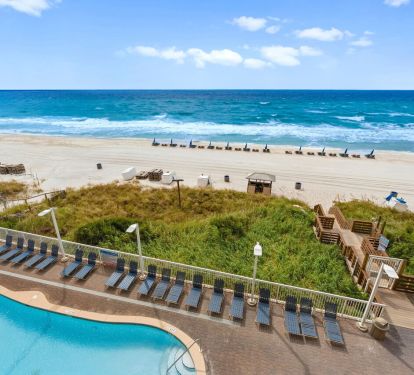 Resort pool overlooking dune walkover, beach chairs, and Gulf waves