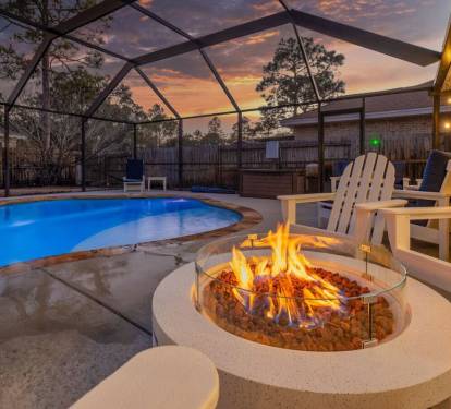 Polywood adirondack chairs around gas fire pit near private heated and screened-in pool.