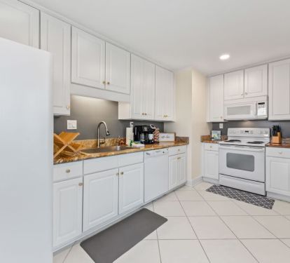 The Seabreeze Villa kitchen is bright and welcoming, featuring crisp white cabinets, marble-inspired countertops, and gold accents. Equipped with modern essentials, including a coffee station to start your mornings right. â˜•âœ¨