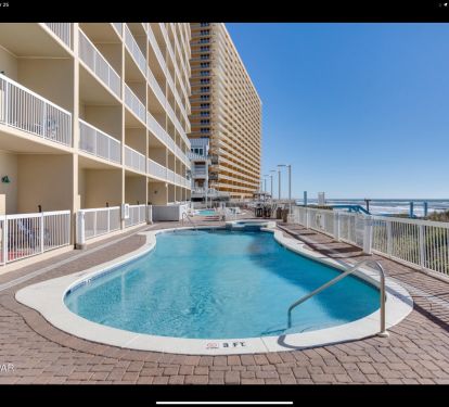 Oceanfront pool with lounge chairs, coastal views, and direct beach access