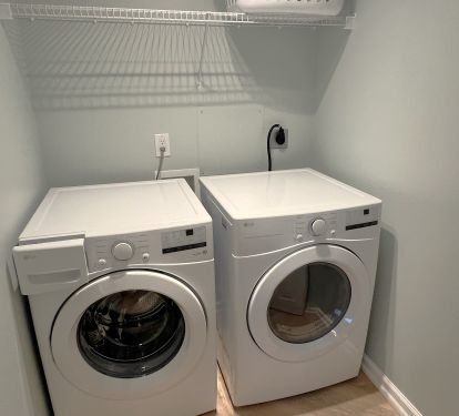 New front load large capacity washer and dryer in an enclosed laundry room.