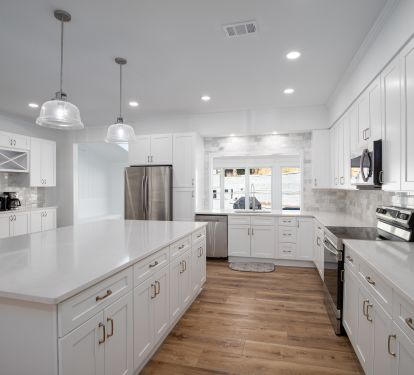 Bright kitchen with tile backsplash and quartz countertops.