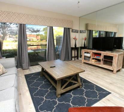 Spacious living room with large windows that let in natural light and flat screen TV