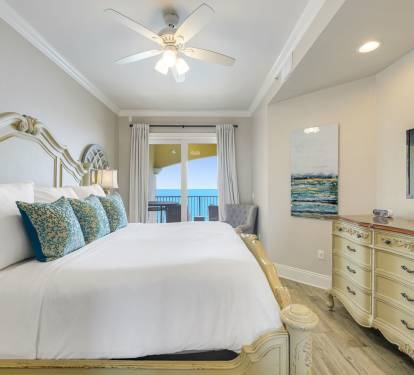 Bright coastal master bedroom with king size bed, private ocean view balcony, and serene beach inspired d-cor