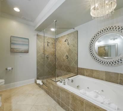 Master bathroom featuring a glass enclosed walk in shower, soaking jetted tub, and elegant double vanity