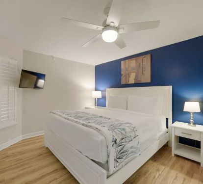Walk into your master bedroom at Cabana Club 205 featuring a king bed, bold coastal blue accent wall, and serene beach-inspired d-cor in Destin, Florida.