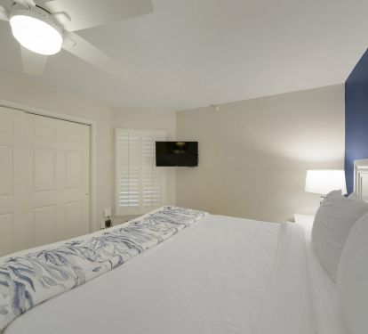 This beautifully designed bedroom blends clean white finishes with a striking navy accent wall for a true coastal luxury feel.