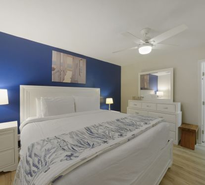 Enjoy a quiet escape in Cabana Club 205-s spacious primary suite, complete with a ceiling fan, dresser, and private access to the bathroom.