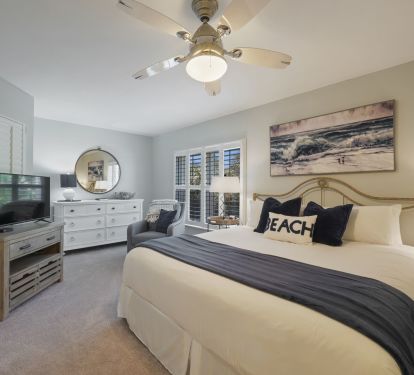 This spacious primary suite offers a king size bed, flat screen TV, and elegant beach-inspired furnishings perfect for your Emerald Coast vacation.