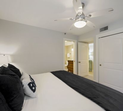 This serene Master bedroom offers a comfortable bed, ceiling fan, and convenient access to a nearby full bathroom.