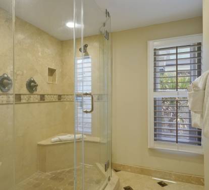 The beautifully tiled shower includes a convenient seating ledge and niche storage, combining style and functionality for your beach getaway.