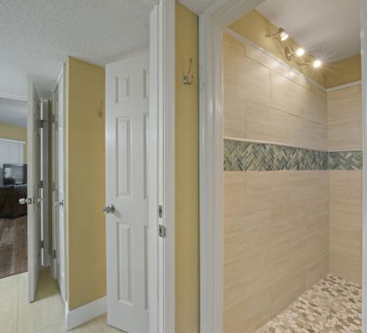 Stylish guest shower with designer tile, pebble-style flooring, and bright lighting for a spa-like experience.