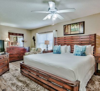 This spacious bedroom blends rustic wood furniture with modern coastal touches. Plush bedding, soft area rug, and ample storage create a comfortable and functional retreat