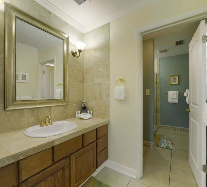 Clean, well-lit beach condo bathroom with granite countertops and ample storage.