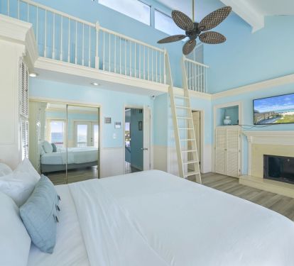 Drift to sleep beneath soaring ceilings in this stunning coastal loft bedroom, where soft sea colors and sunlight create a peaceful retreat after long days on the beach.