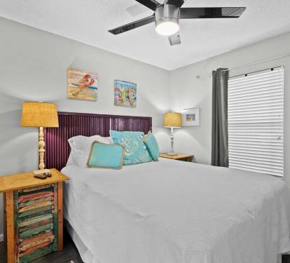 Cozy second bedroom with queen bed, coastal accents, and warm lighting.