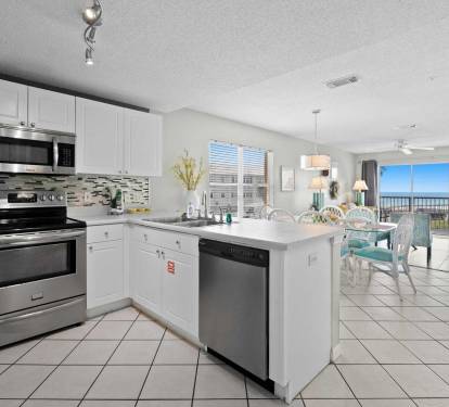 Modern kitchen with stainless steel appliances and an open layout that flows into the dining and living areas with Gulf views