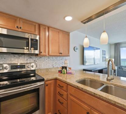 Open coastal living area at Cabana Club 307 in Destin, Florida showcasing a fully equipped kitchen, dining table, and stunning ocean views of the white sand beaches.