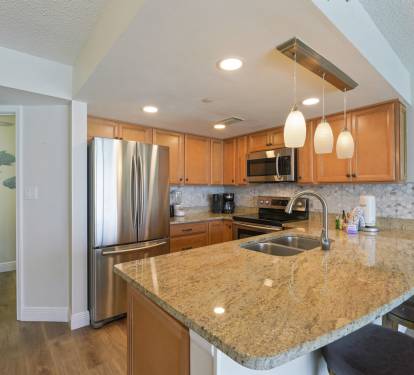 The open-concept kitchen and living area at Cabana Club 304 features granite countertops, full appliances, and stunning Gulf views from the balcony.