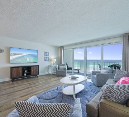 The coastal-inspired living space features comfortable seating, flat-screen TV, and floor-to-ceiling sliding doors to the beach balcony.